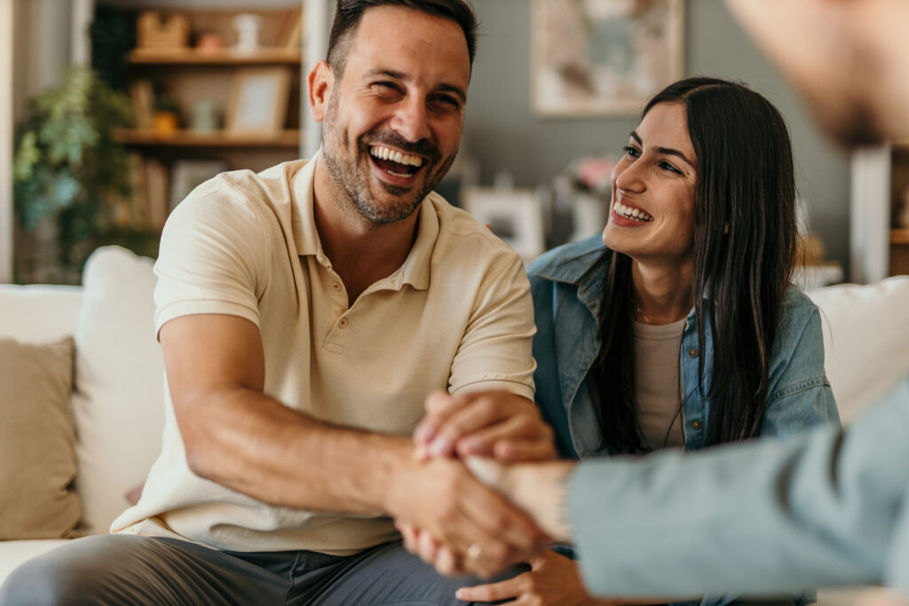 Glückliches Pärchen, dass nebeneinander sitzt und eine Hand schüttelt